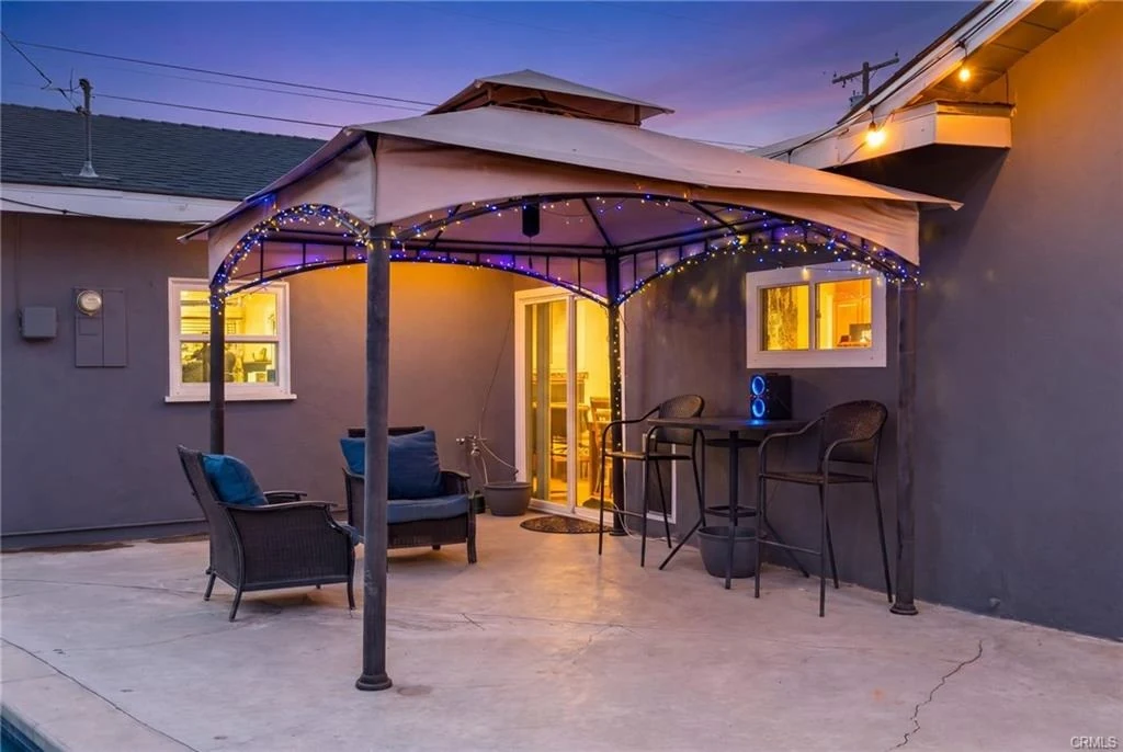 Covered backyard patio beside the pool at dusk